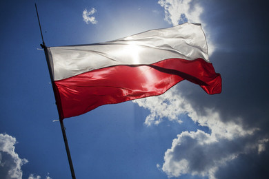 Flaga Polski biało czerwona na tle niebieskiego nieba.