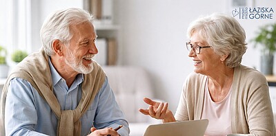 Dwoje seniorów kobieta i mężczyzna siedzi i rozmawia.