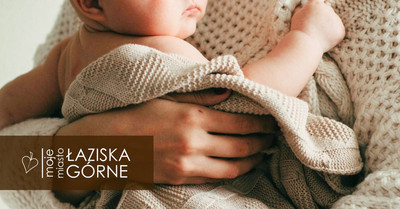 Niemowlę owinięte miękkim, dzianinowym kocem trzymane w rękach dorosłej osoby delikatnie.