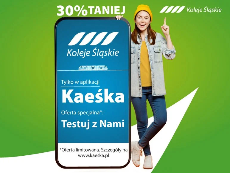 Testuj aplikację kaeśka. Uśmiechnięta młoda kobieta stoi obok ogromnego smartfona. Na ekranie informacja o aplikacji Kaeśka i zniżce 30% na bilety - szczegóły w treści artykułu